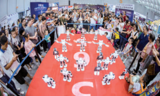 “互聯(lián)網(wǎng)+”博覽會展館內(nèi)，市民圍觀跳集體舞的機器人。/珠江商報記者資料圖（記者周焯杰攝）