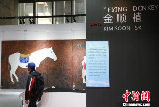 韓國參展企業(yè)展位前，一位游客正在欣賞作品?！〗獫?攝